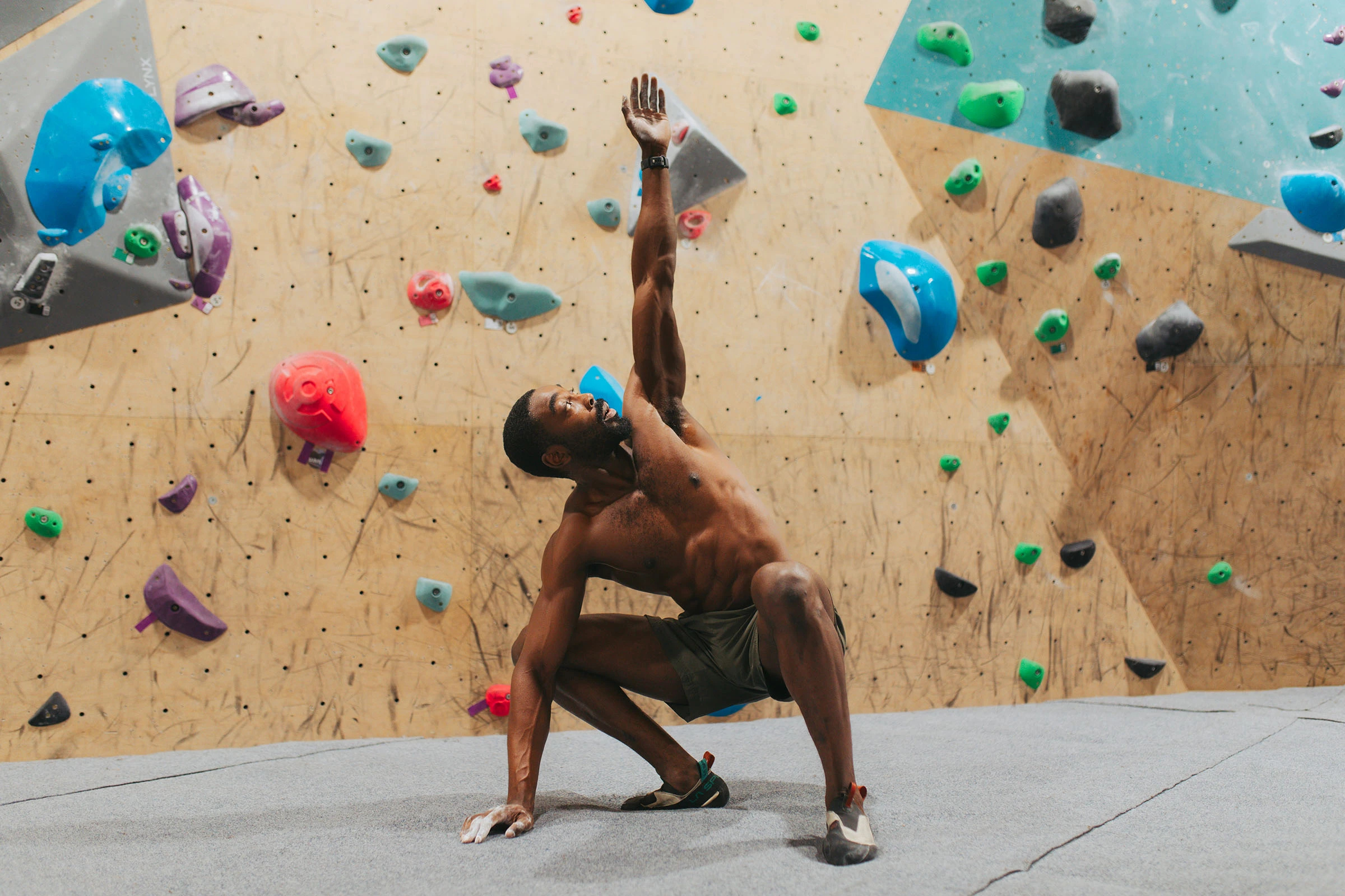 Rotimi stretching in front of a climbing wall