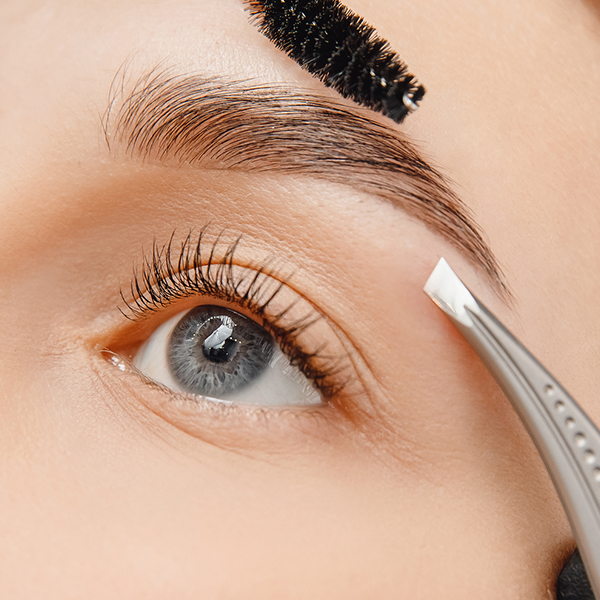 Woman with blue eyes getting her brows shaped at home