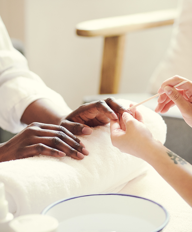 Hands resting on towel as nails treated using a cuticle stick