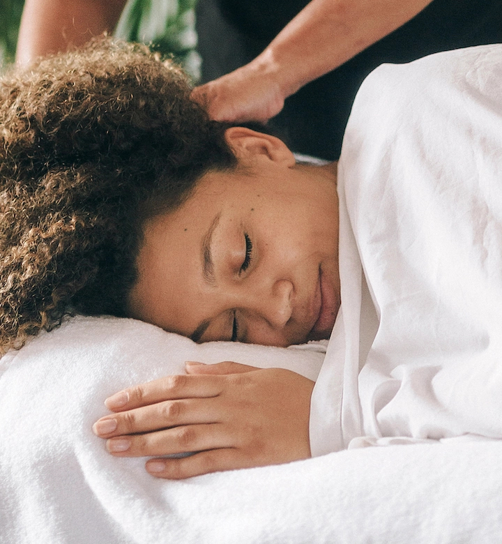 Client relaxes on a massage table as part of a postnatal massage