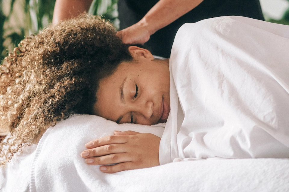 Pregnant client is smiling as she receives a relaxing head massage