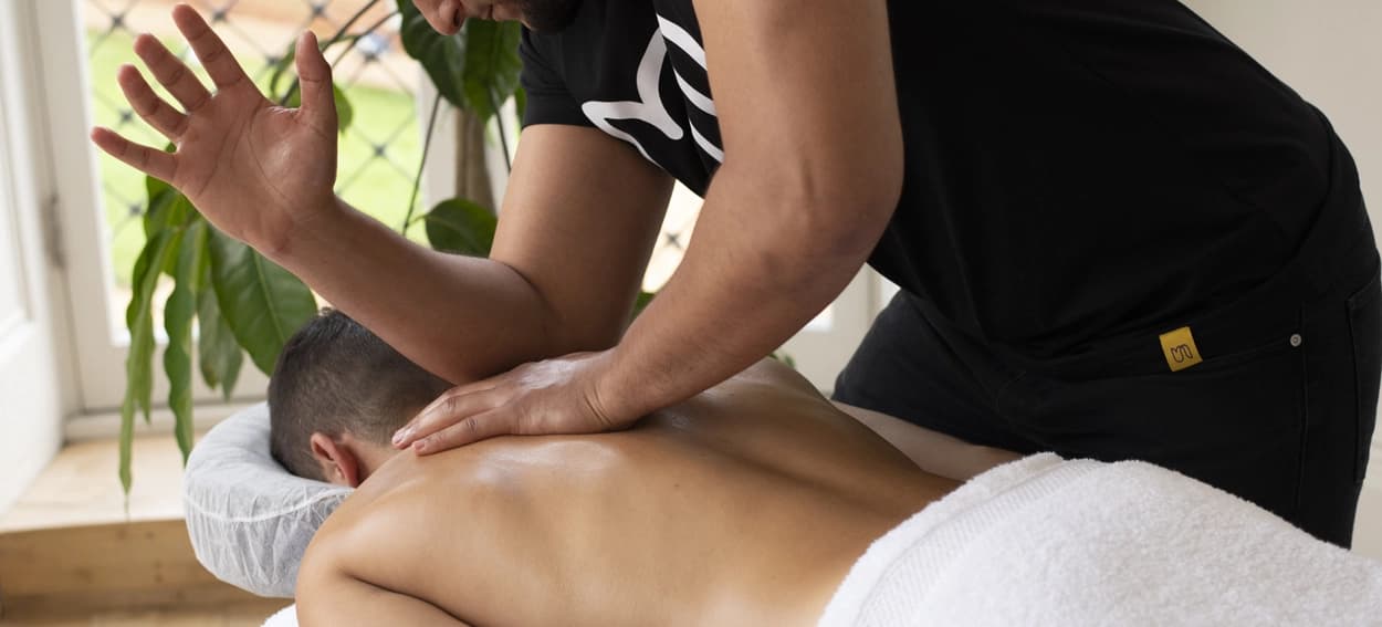 Deep tissue massage pressure demonstrated by male therapist using elbows