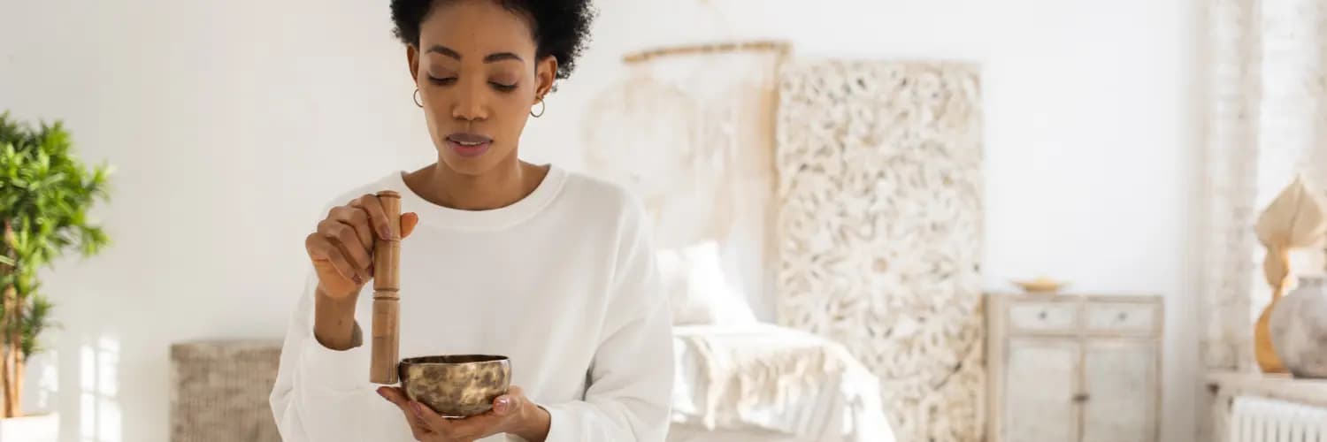 Woman sitting comfortably using a sound bath in her bedroom