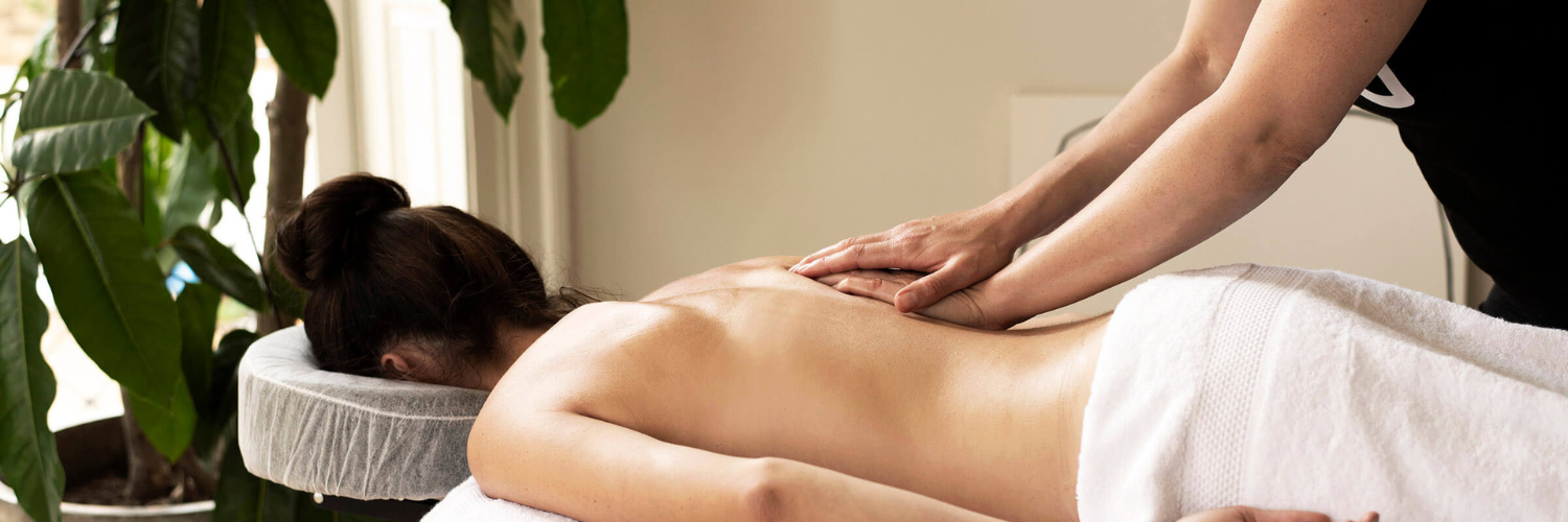 Woman on massage table getting a de-stress massage with plants in the background