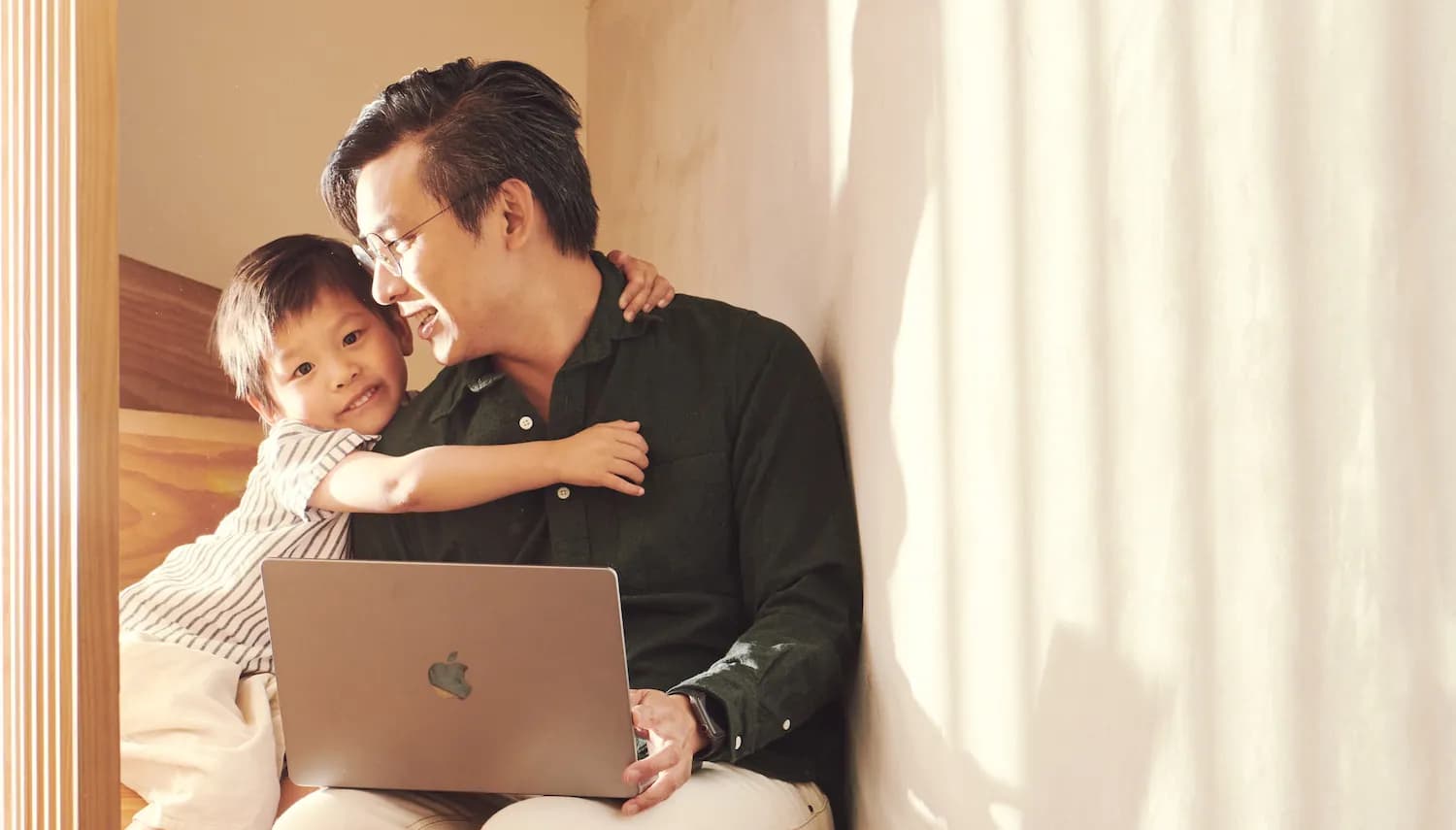 Father and son sitting in a wooden stairwell lit by golden light