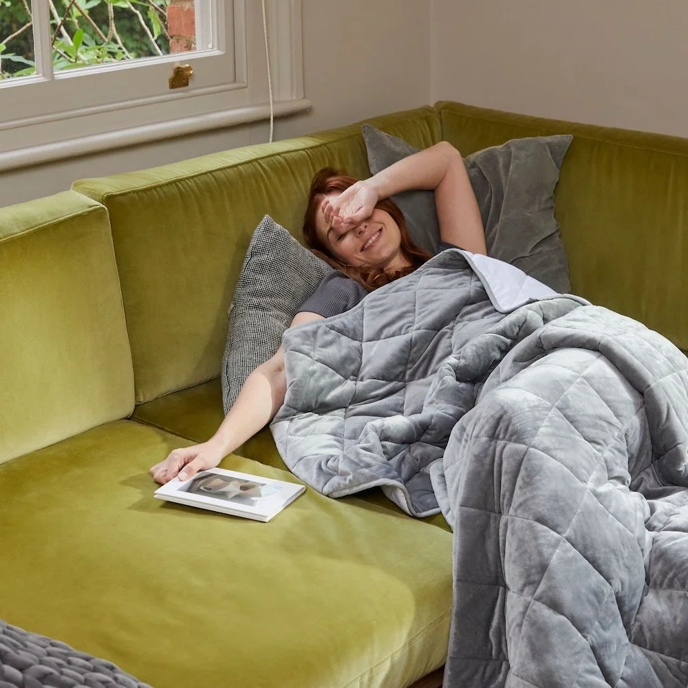 woman relaxing on sofa under weighted blanket