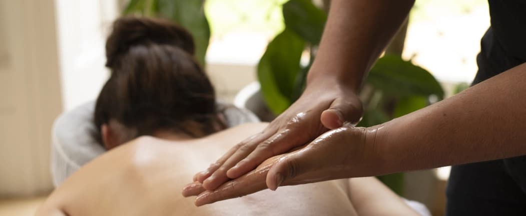 Massage therapist prepares oil in their hands for a swedish massage