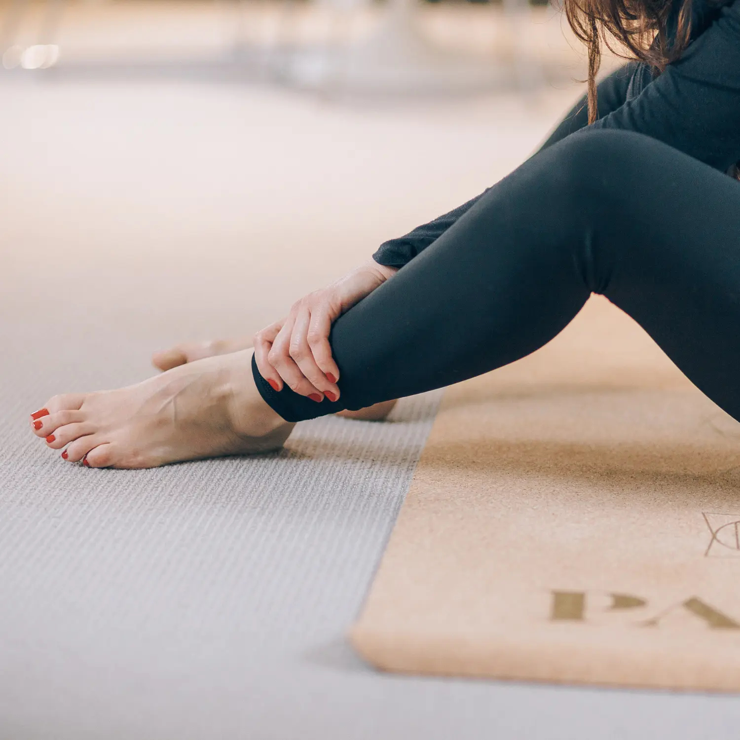 Woman sitting on yoga mat trying to touch toes