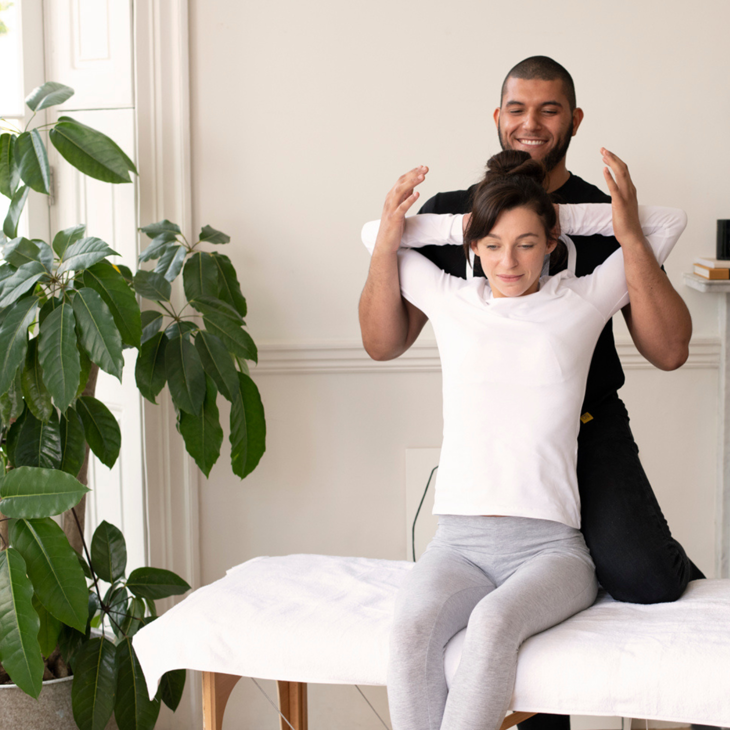 Therapist stretches client's back during an assisted stretching session at home