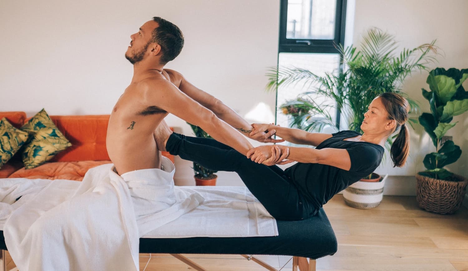 Thai massage therapist stretches client's tight back muscles 