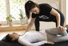 Stretch therapist performs assisted stretching by moving client into a twist position