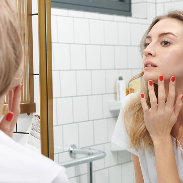 Woman at home, looking in the mirror, with freshly waxed chin