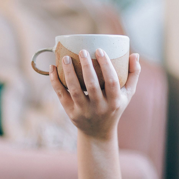 Manicured hand holding a ceramic mug