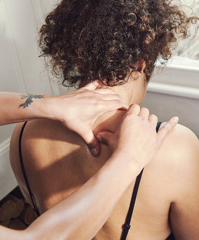 Woman facing window having shoulders massaged