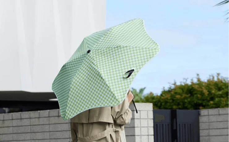 Woman walks with a blunt umbrella in green and white check