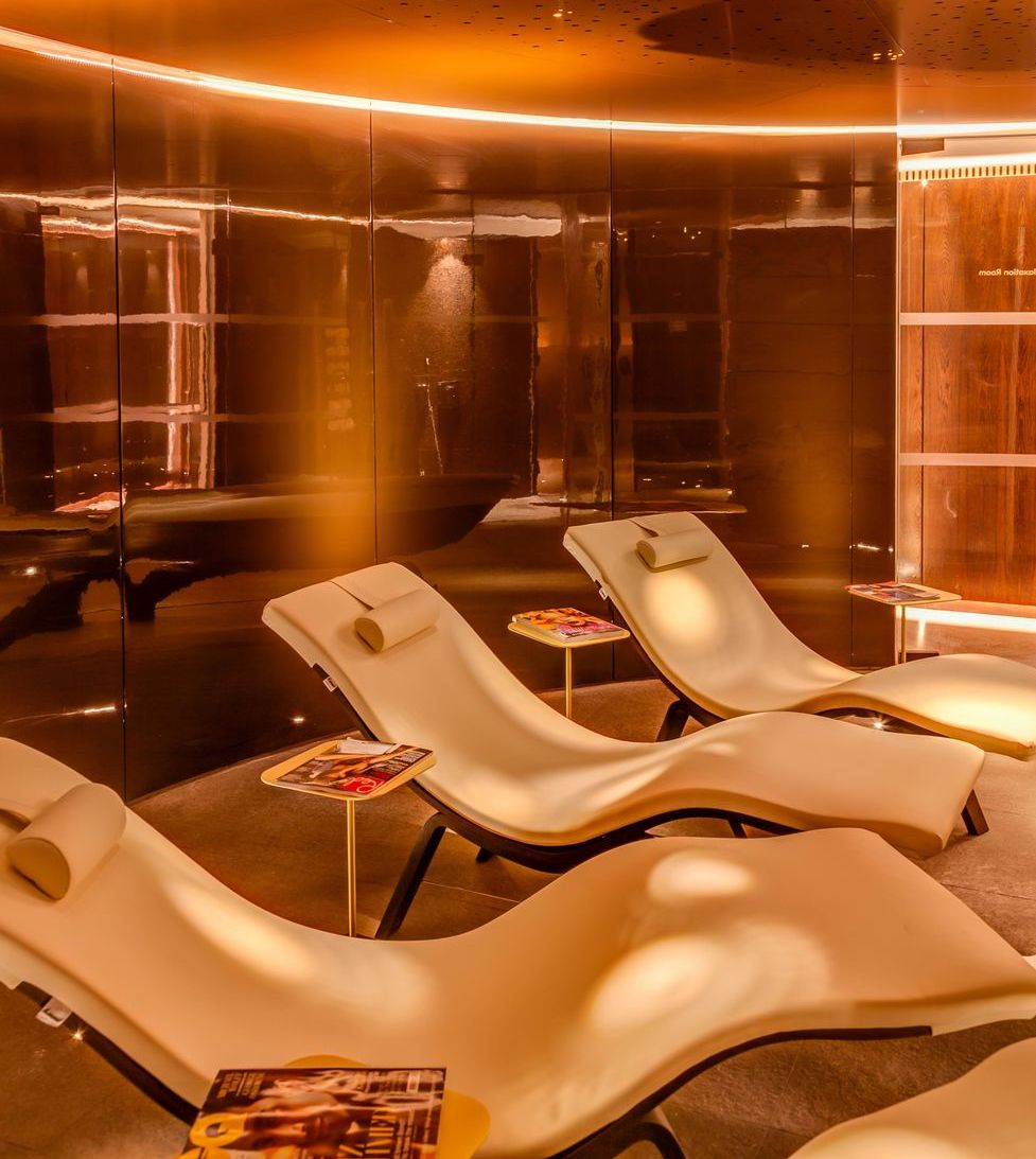An inviting spa relaxation area with amber lighting and recliners with glossy magazines to read
